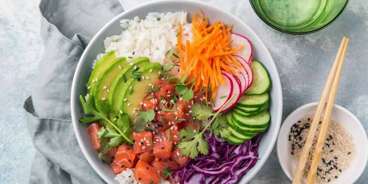 Kolorowy poke bowl: ryż, łosoś, awokado, marchewka, rzodkiewka, ogórek i czerwona kapusta. Idealny posiłek, który zaspokoi głód.