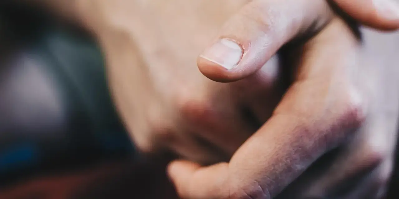 Dita intrecciate, un primo piano che evoca il senso di vibrazione interna e le sue cause, forse ansia o attesa.