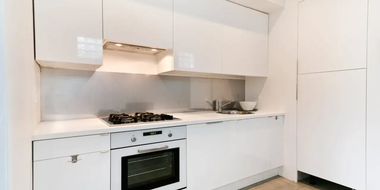 Cuisine moderne blanche avec hotte intégrée au-dessus de la plaque de cuisson. La hauteur de la hotte cuisine est idéale pour une utilisation confortable.