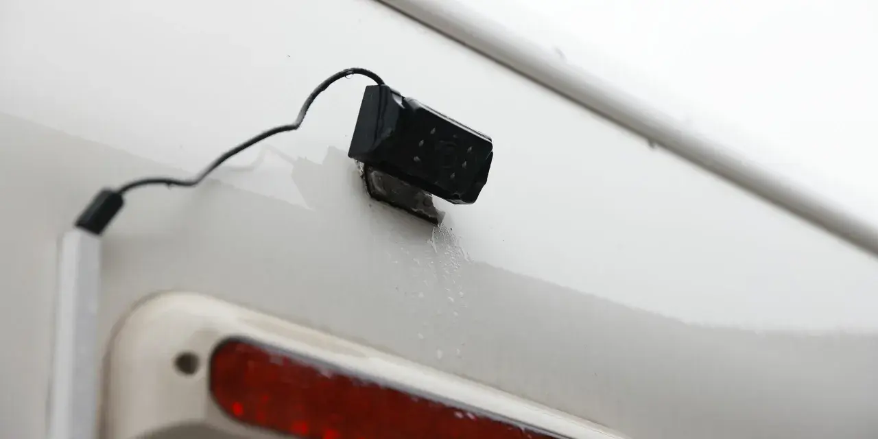 En liten svart backkamera monterad på en vit yta, redo att installera för bättre sikt bakåt.