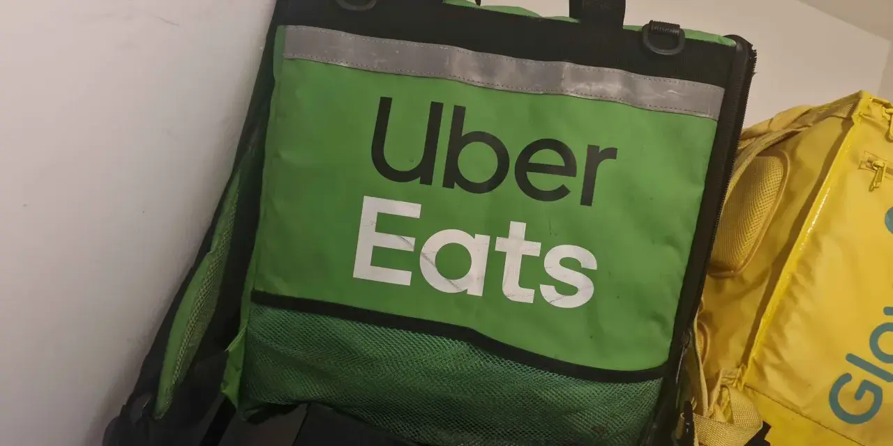 Zielona torba Uber Eats, obok żółtej torby Glovo. Taki widok może oznaczać potencjalne uber eats zarobki.