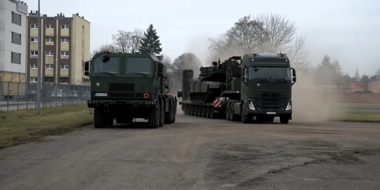 Dwa wojskowe pojazdy, w tym potężny Volvo FH16, transportują ciężki sprzęt.