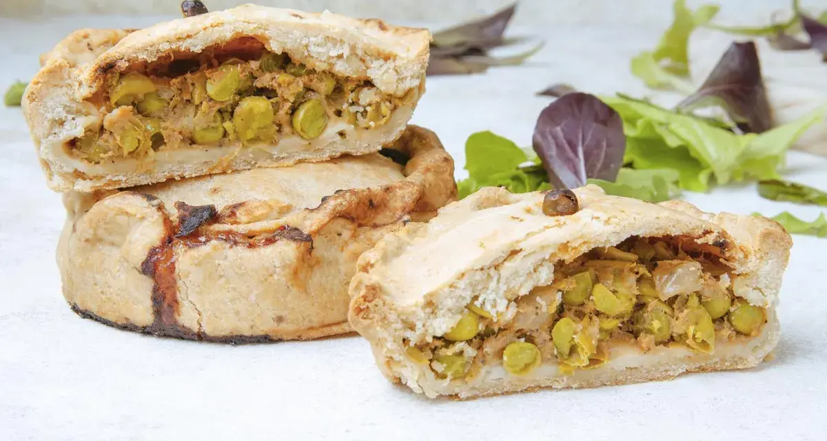 Panades mallorquinas cortadas, mostrando el relleno de guisantes y carne.