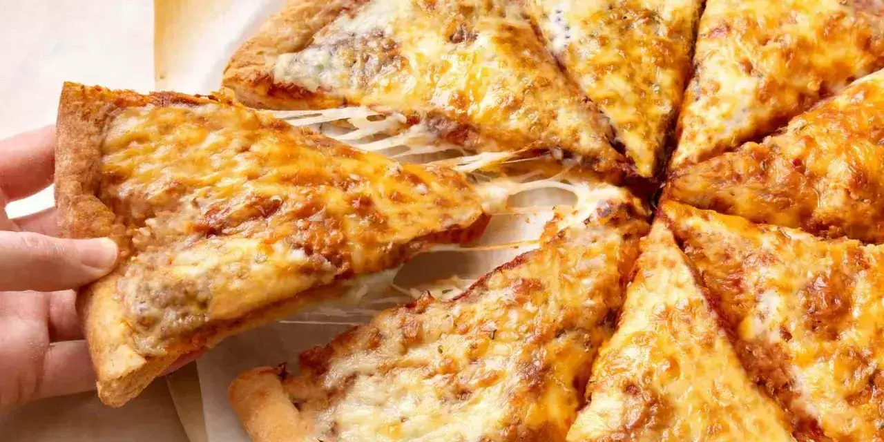 Pyszne, gorące ciasto na pizzę z ciągnącym się serem, które właśnie jest podnoszone.