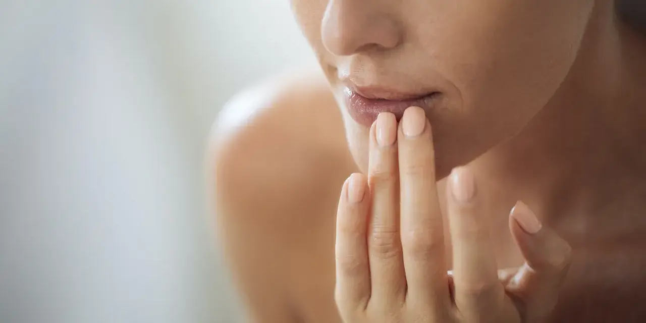 Nahaufnahme einer Frau, die sich mit den Fingern die Lippen berührt. Ein sanfter Blick auf natürliche Schönheit, vielleicht inspiriert von hausmittel gegen falten.