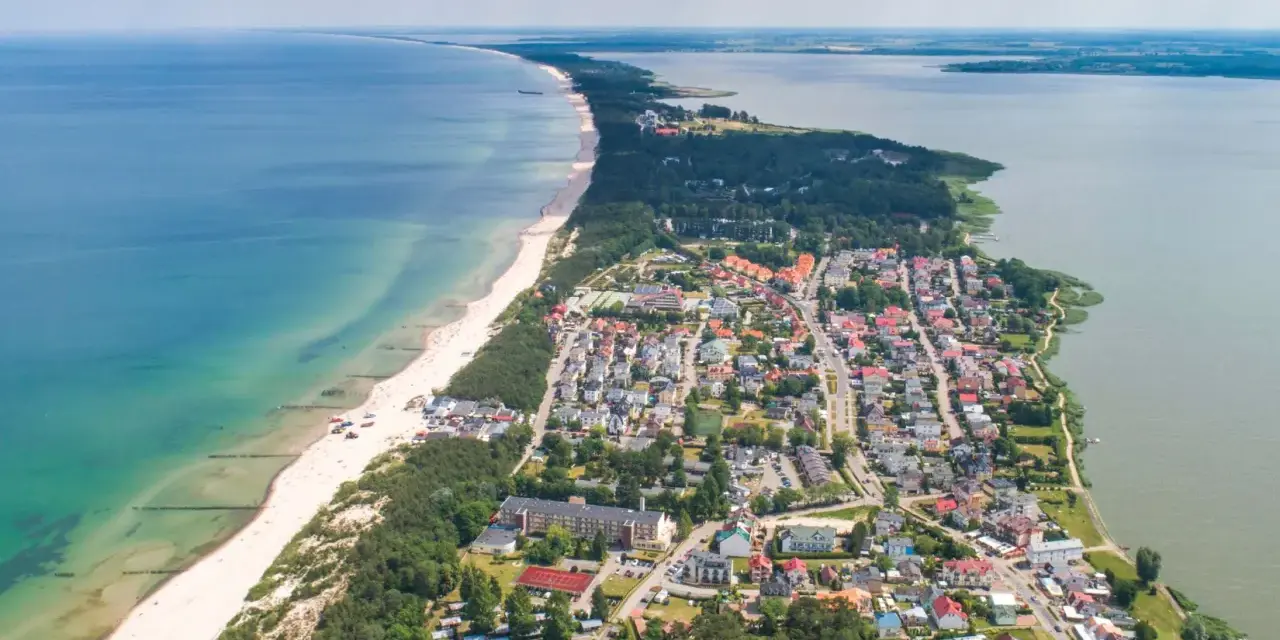 Widok z lotu ptaka na Mielno: plaża, morze, jezioro i zabudowania.