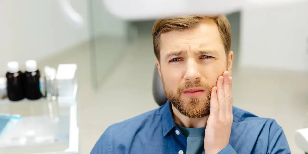 Mężczyzna z bólem zęba po zatruciu, szuka pomocy.