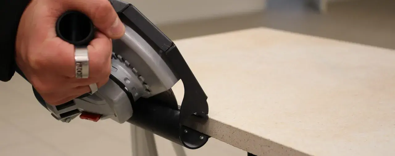 Hand mit Ring hält Winkelschleifer zum präzisen Fliesenschneiden.