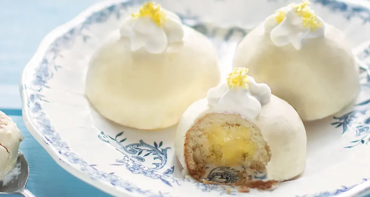 Deliziose tortine al limone, con un ripieno cremoso e una decorazione di panna e scorza di limone.