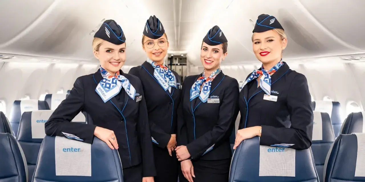 Uśmiechnięte stewardessy Enter Air w granatowych mundurkach. Opinie forum o Enter Air często chwalą miłą obsługę.