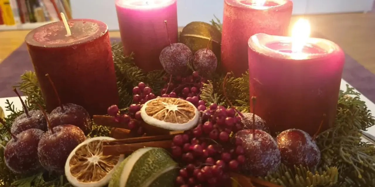 Adventskranz mit vier roten Kerzen, Tannenzweigen, Beeren, getrockneten Früchten und kleinen Äpfeln. Der 6. Sonntag nach Ostern ist noch weit, aber die Vorfreude auf Weihnachten ist spürbar.