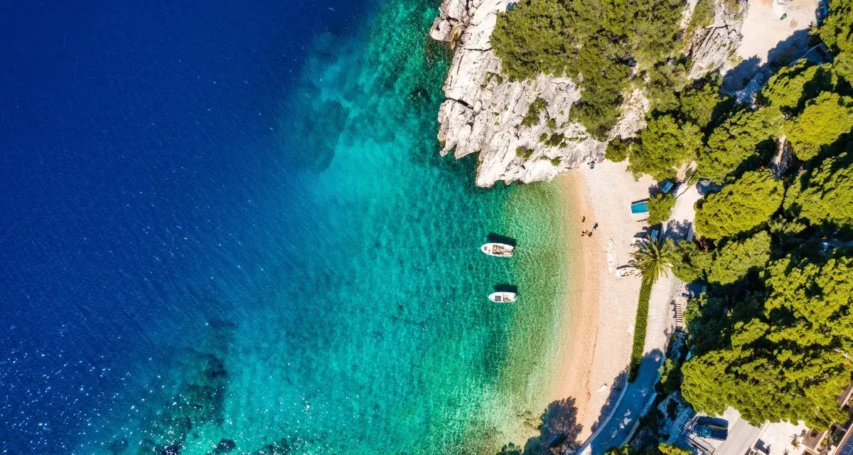 Chorwacja gdzie na wakacje? Rajska plaża z krystalicznie czystą wodą, łódkami i zielonymi wzgórzami. Idealne miejsce na relaks.