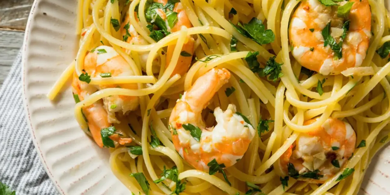 Un piatto invitante di pasta con gamberetti, condita con prezzemolo fresco e un filo d'olio.