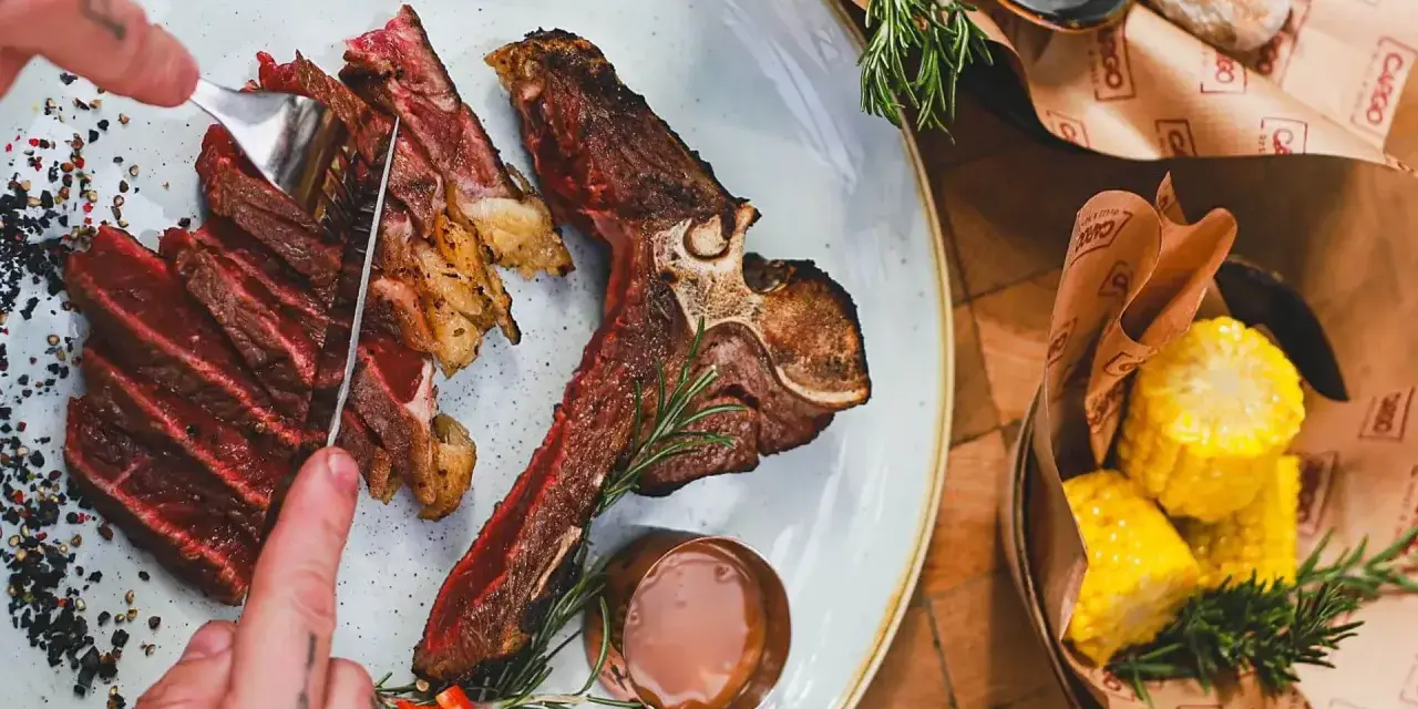 Idealne jakie wino do steka? Soczysty stek T-bone z pieczonymi kolbami kukurydzy i sosem.