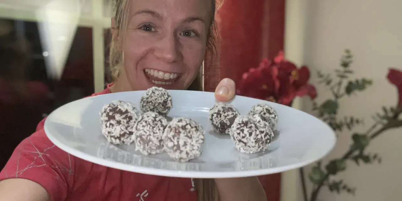 Glad kvinna visar upp en tallrik med hemgjorda chokladbollar, perfekta för ett snabbt och enkelt chokladbollar recept.