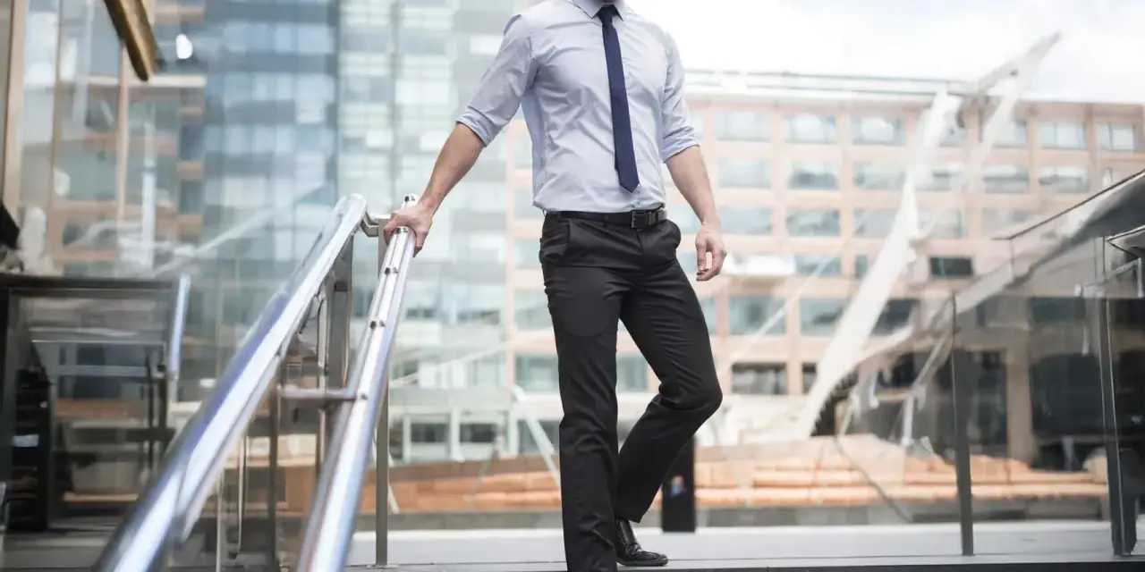 Uomo con pantaloni neri come abbinarli: camicia azzurra e cravatta blu, un look da ufficio moderno.