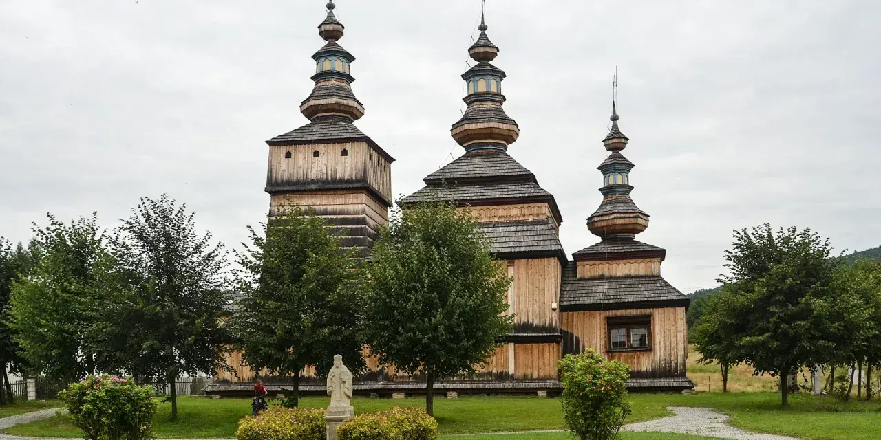 Drewniana cerkiew z trzema kopułami, otoczona zielenią. Wspaniałe krempna atrakcje dla miłośników historii i architektury.
