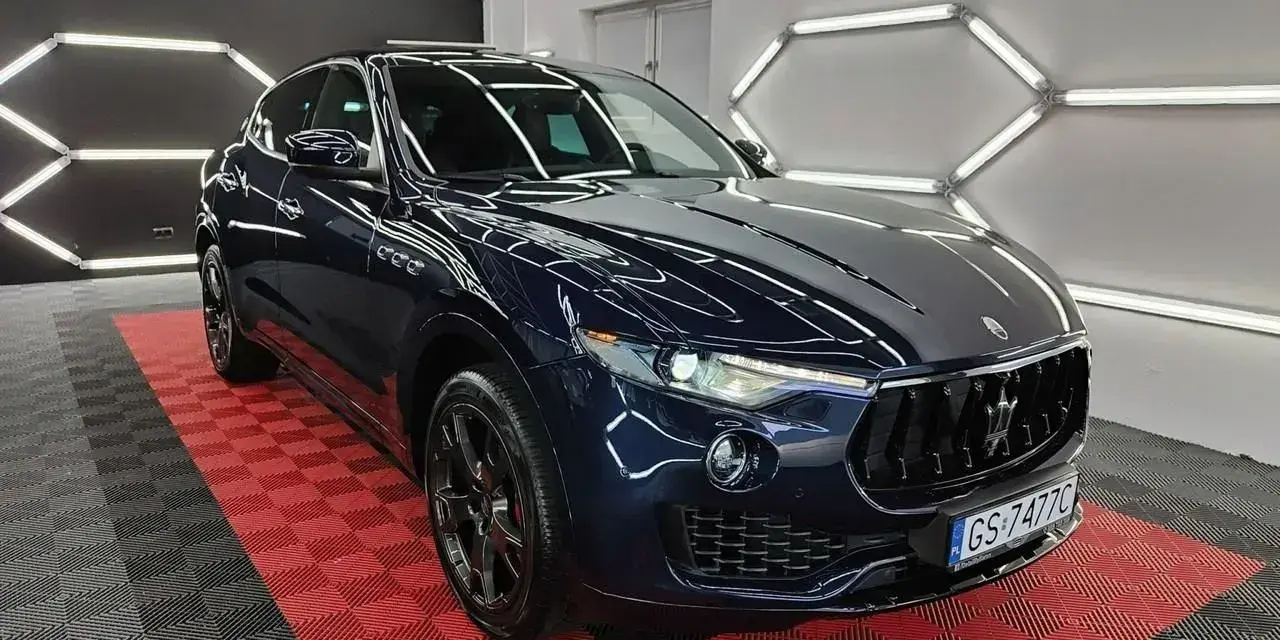 Lśniący, granatowy Maserati Levante na czerwono-czarnej podłodze. Sprawdź aktualną maserati levante cena i poczuj luksus.