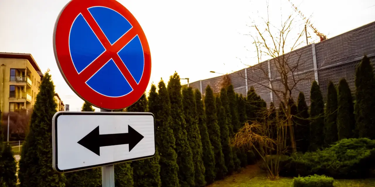Znak zakaz parkowania z tabliczką wskazującą kierunki.