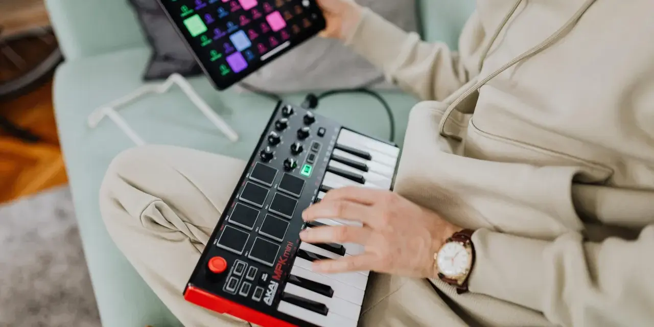 Osoba tworzy muzykę na kontrolerze midi usb. To świetny sposób na rozpoczęcie przygody z produkcją muzyczną.