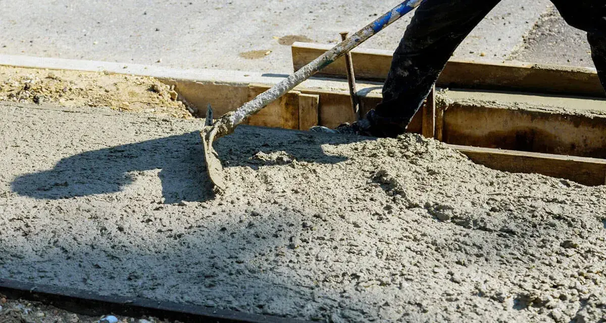Pracownik rozprowadza świeży beton B25. Czas wiązania betonu zależy od wielu czynników.