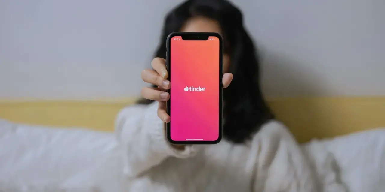 Dłoń trzyma telefon z logo Tindera. Zastanawiasz się, czemu nie mogę usunąć konta na Tinderze?