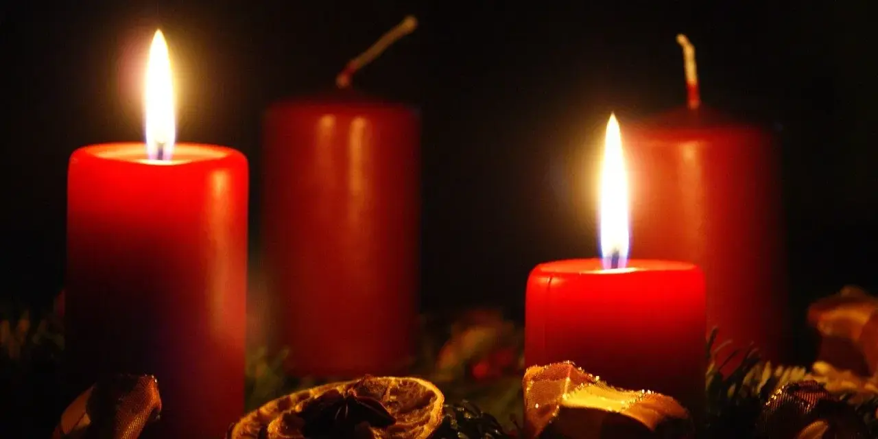Two red candles glow, marking the 2nd advent. A festive wreath with dried orange slices and pine needles surrounds them.