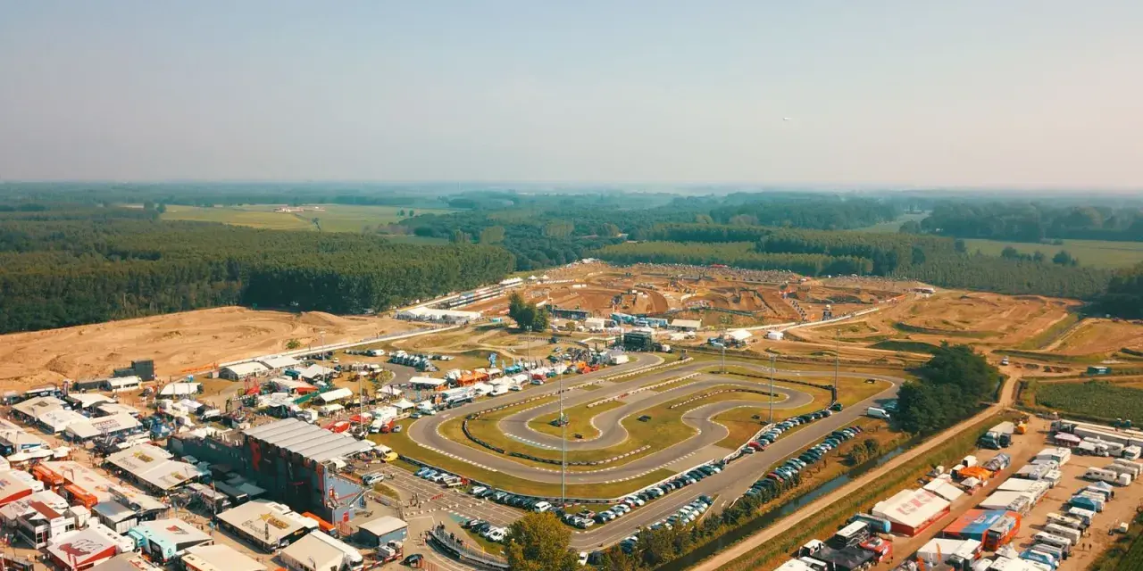 Vista aerea di un circuito **ottobiano motorsport** con paddock, tribune e pista da cross sullo sfondo, immerso nel verde.