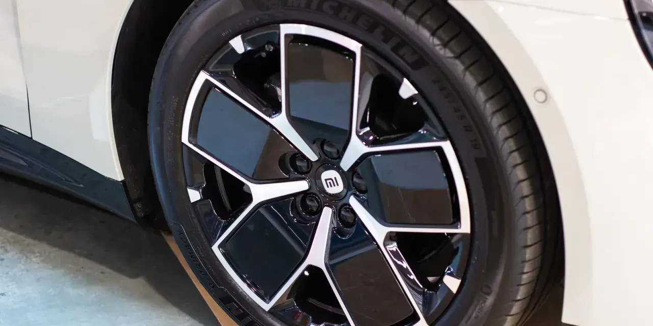 Pneu Michelin sur jante noire et argentée avec logo Mi sur une voiture blanche.