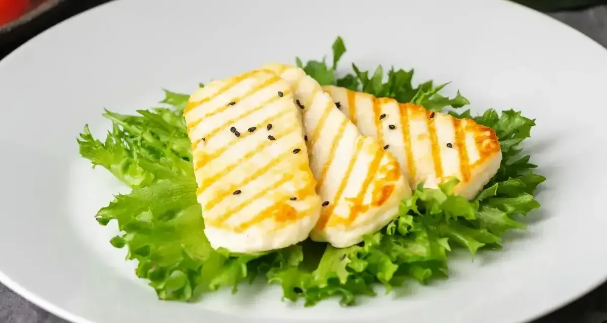Grillowany ser halloumi na sałacie, posypany czarnuszką. Czy ser halloumi jest zdrowy? To pyszna przekąska.