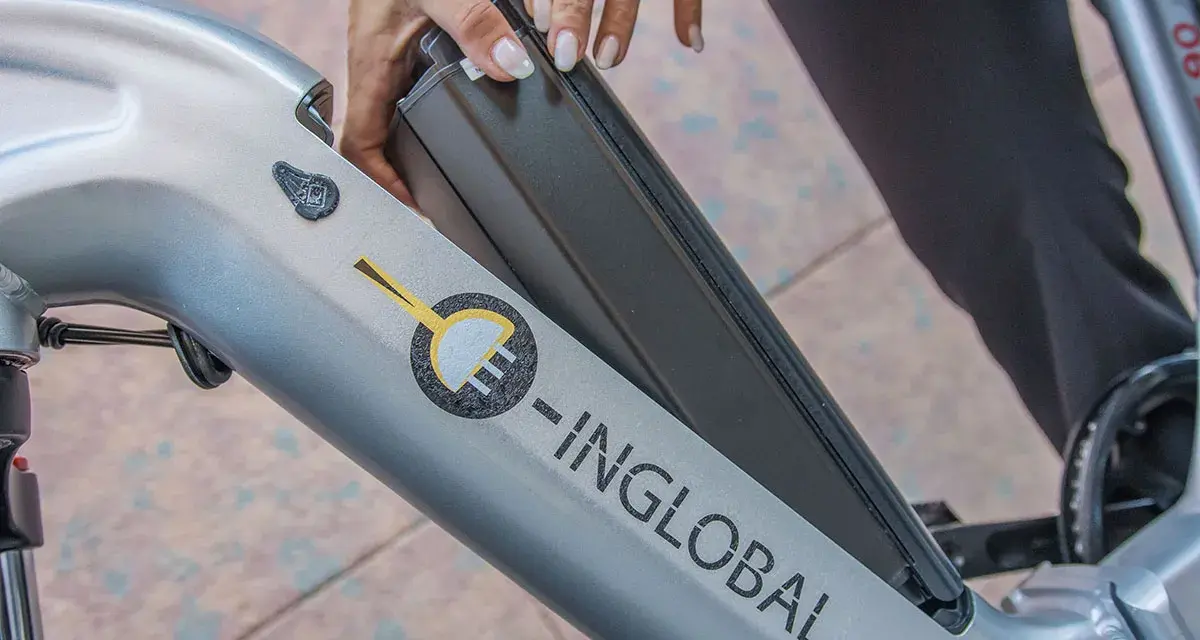 Mani che inseriscono la batteria in una bici elettrica. La durata della batteria di una bici elettrica è fondamentale per l'autonomia.