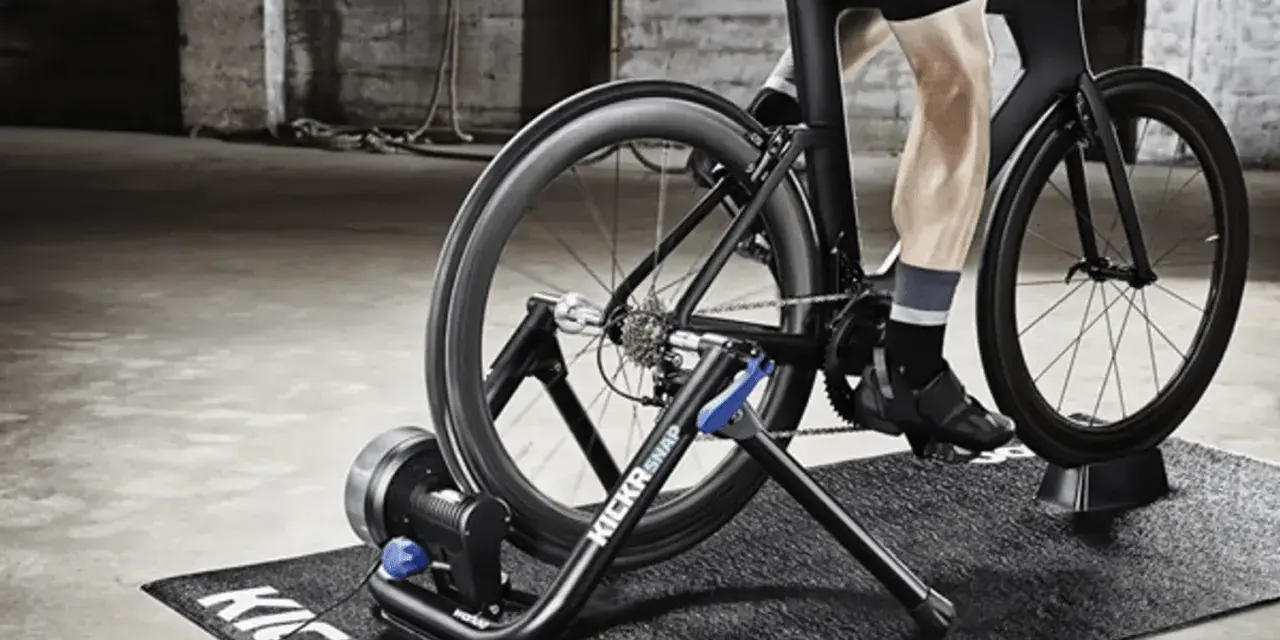 A person is engaged in indoor cycling training on a trainer in a gritty, industrial-style room.