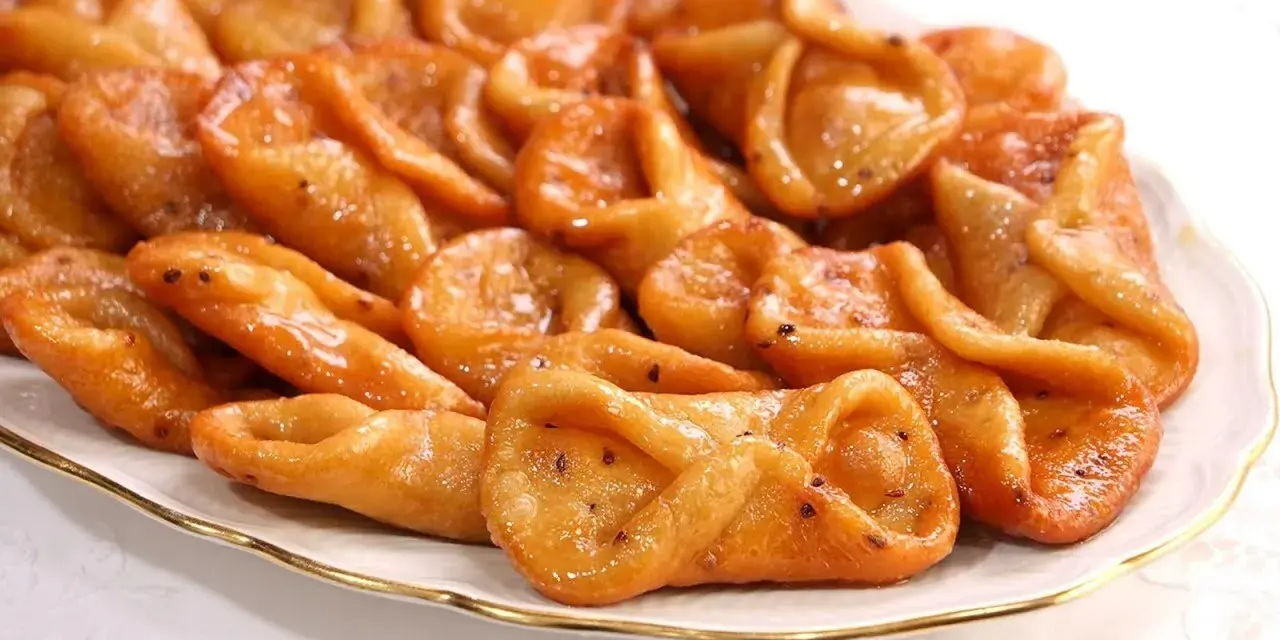 Plato de pestiños antiguos, dorados y brillantes, con un glaseado que los hace irresistibles. Perfectos para acompañar un café.