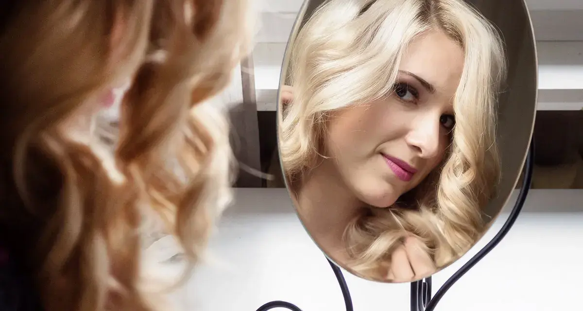 Piękna blondynka z burzą loków, odbijająca się w lustrze. To idealny sposób na loki przez noc.