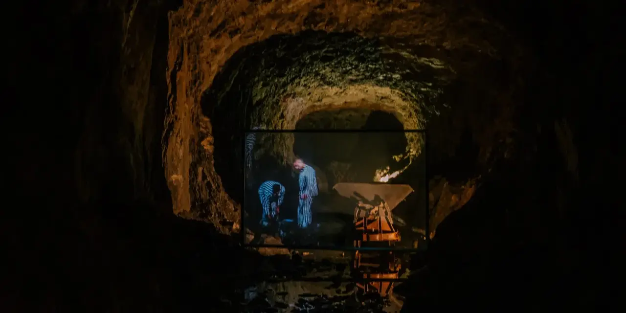 W jaskini wyświetlany jest film, na którym widać dwie postacie w pasiaste ubrania. Czy to osówka czy włodarz?