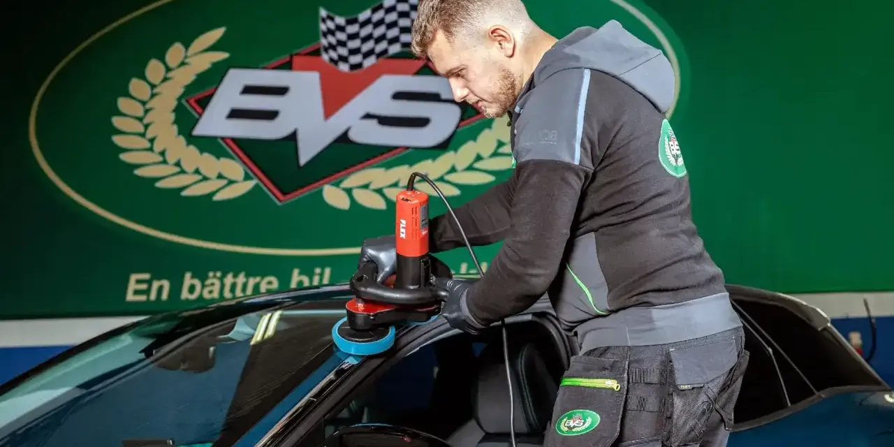 Man polerar en bil med polermaskin. En professionell rekond bil-tjänst som ger nytt liv åt lacken.