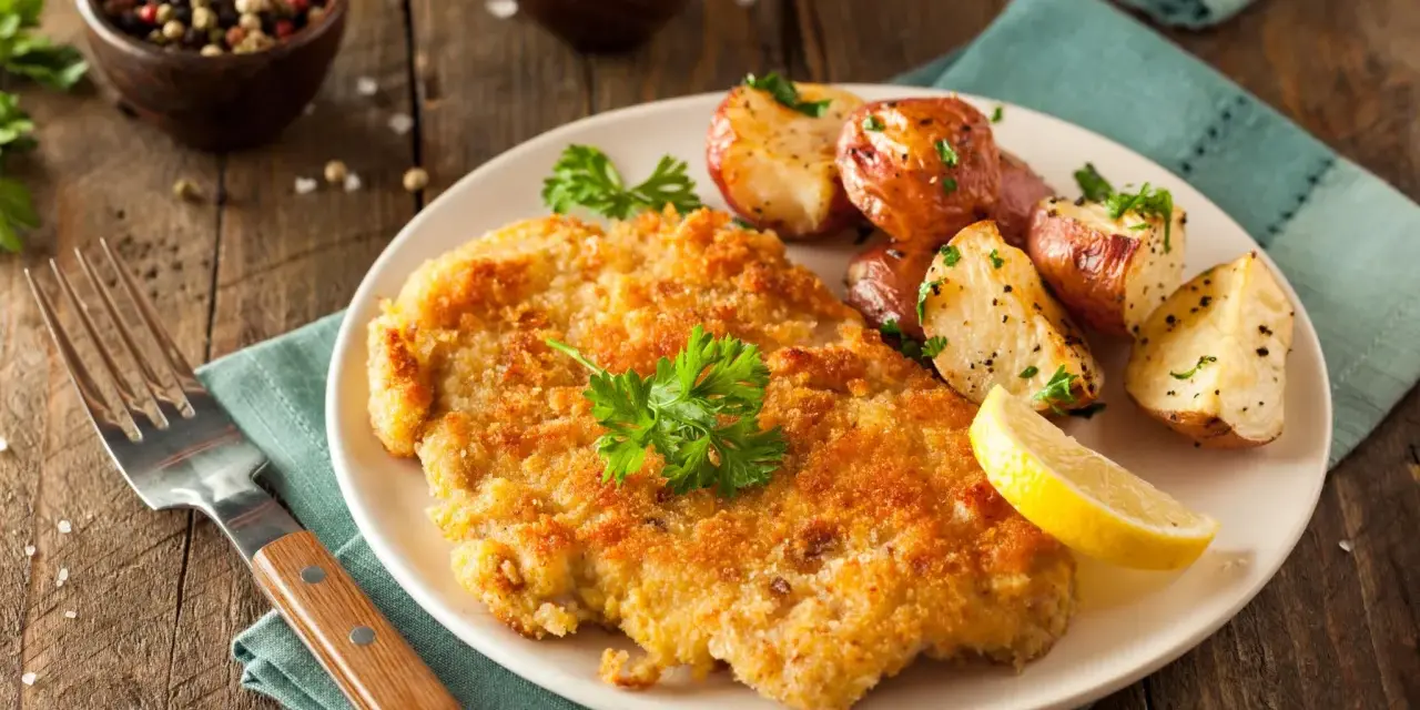 Perfekt paniertes Schnitzel mit Rosmarinkartoffeln und Zitrone. Ein Genuss, der zeigt, wie einfach und lecker Schnitzel panieren sein kann.