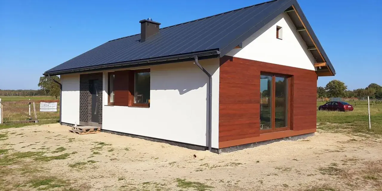 Nowy, nowoczesny dom do 70m2 z drewnianą elewacją i dużymi oknami, gotowy na przyjęcie mieszkańców.