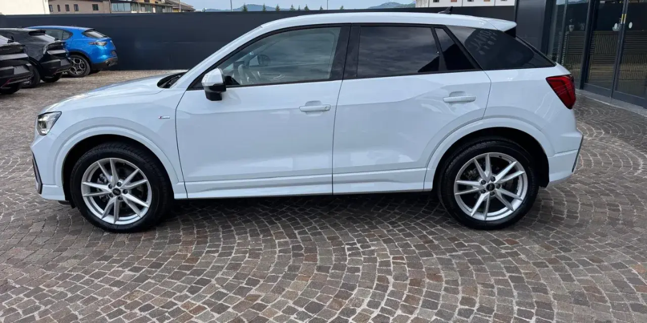 Audi Q2 bianca parcheggiata su pavé. Controlla la pressione pneumatici per un viaggio sicuro.