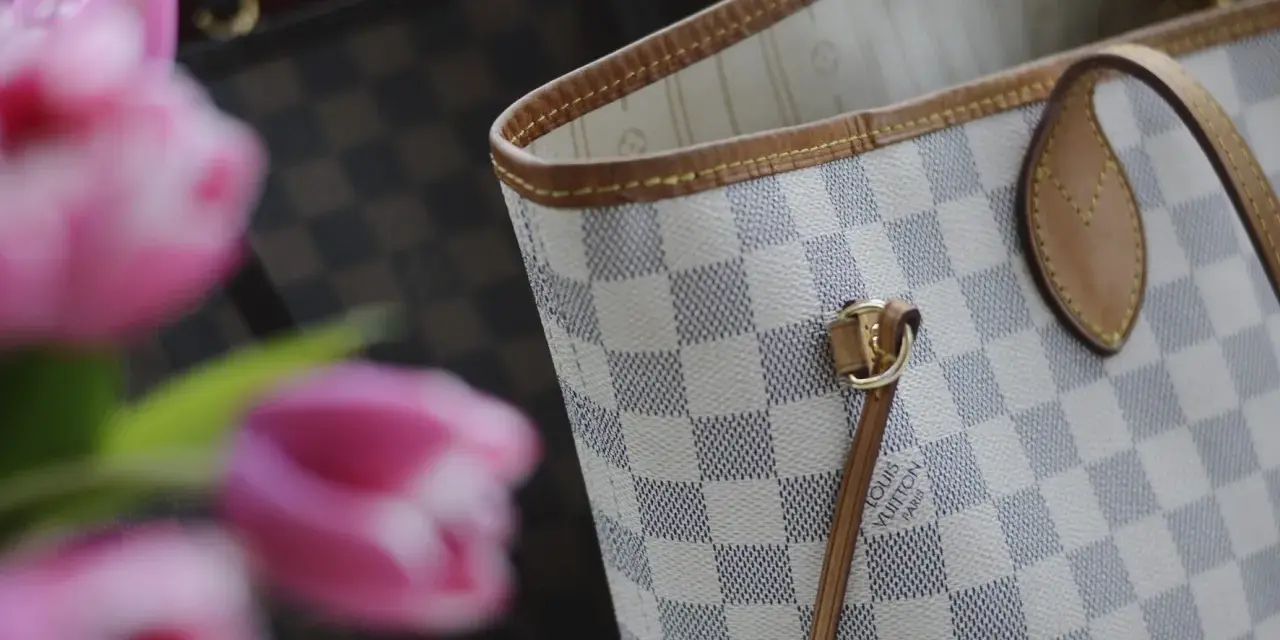 Jasna torebka Louis Vuitton w kratkę Damier Azur z różowymi tulipanami w tle.