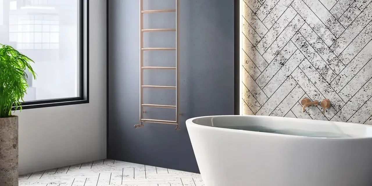 Radiador de agua vertical de cobre, un ejemplo de tipos de radiadores de agua, junto a una bañera y una planta.