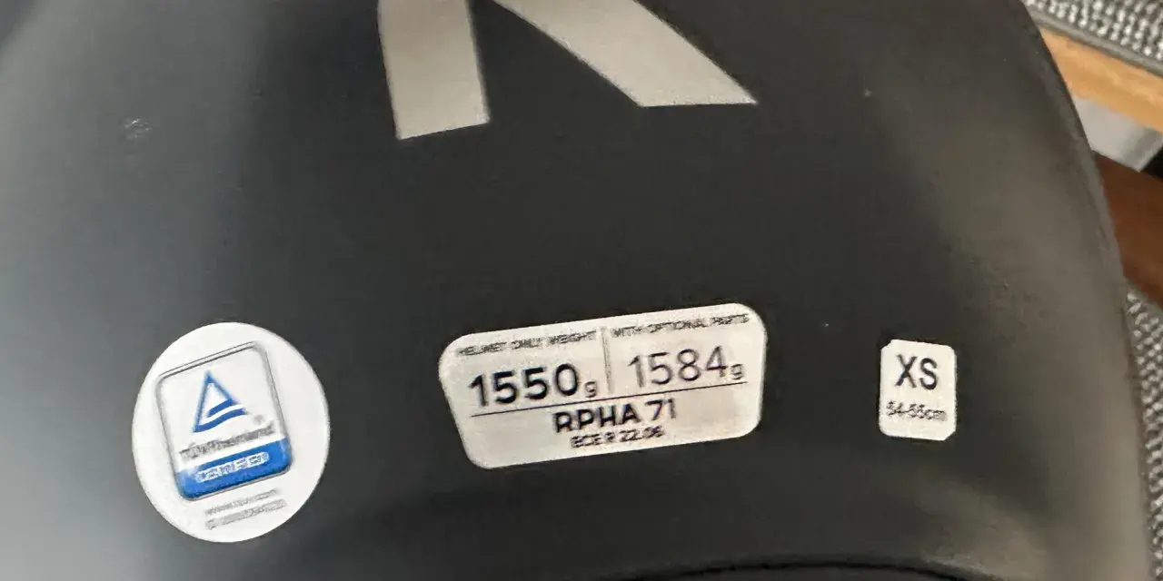 Casco nero con logo R argentato. Etichette indicano peso, modello RPHA 71, certificazione e taglia XS. Sul casco possono essere applicati adesivi.