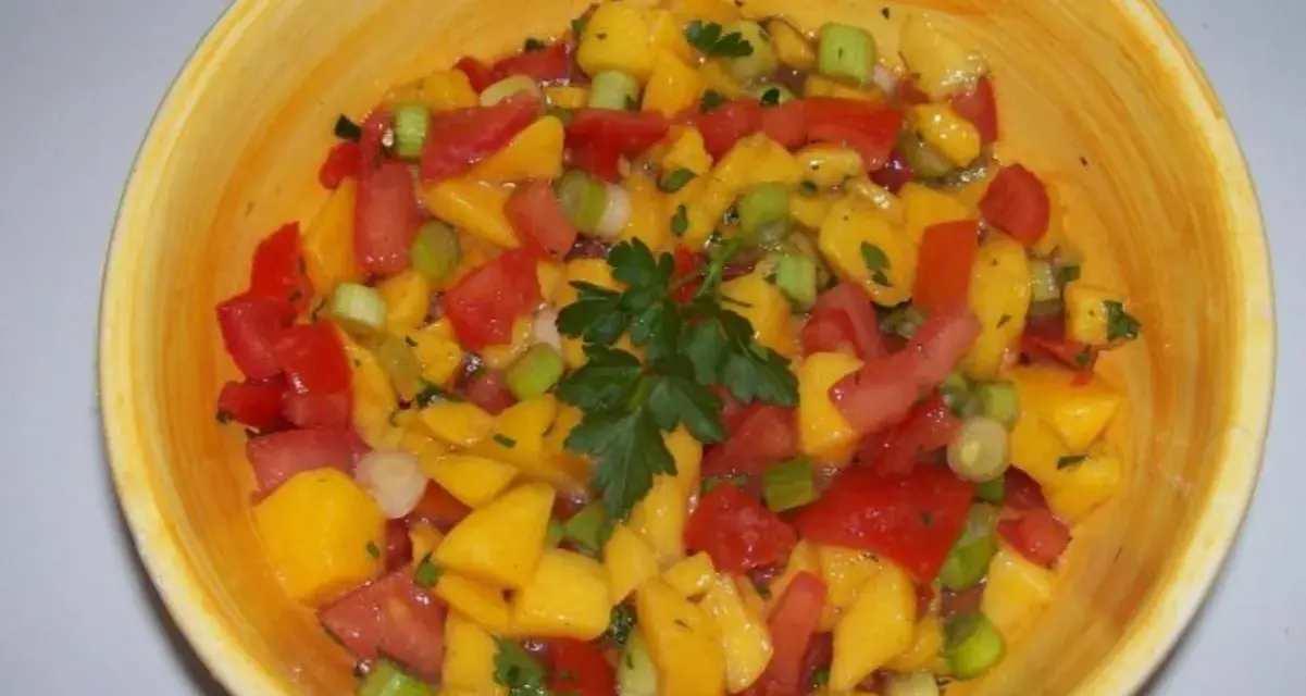 Bunte Mango Salsa mit Tomaten, Frühlingszwiebeln und Petersilie in einer gelben Schüssel.
