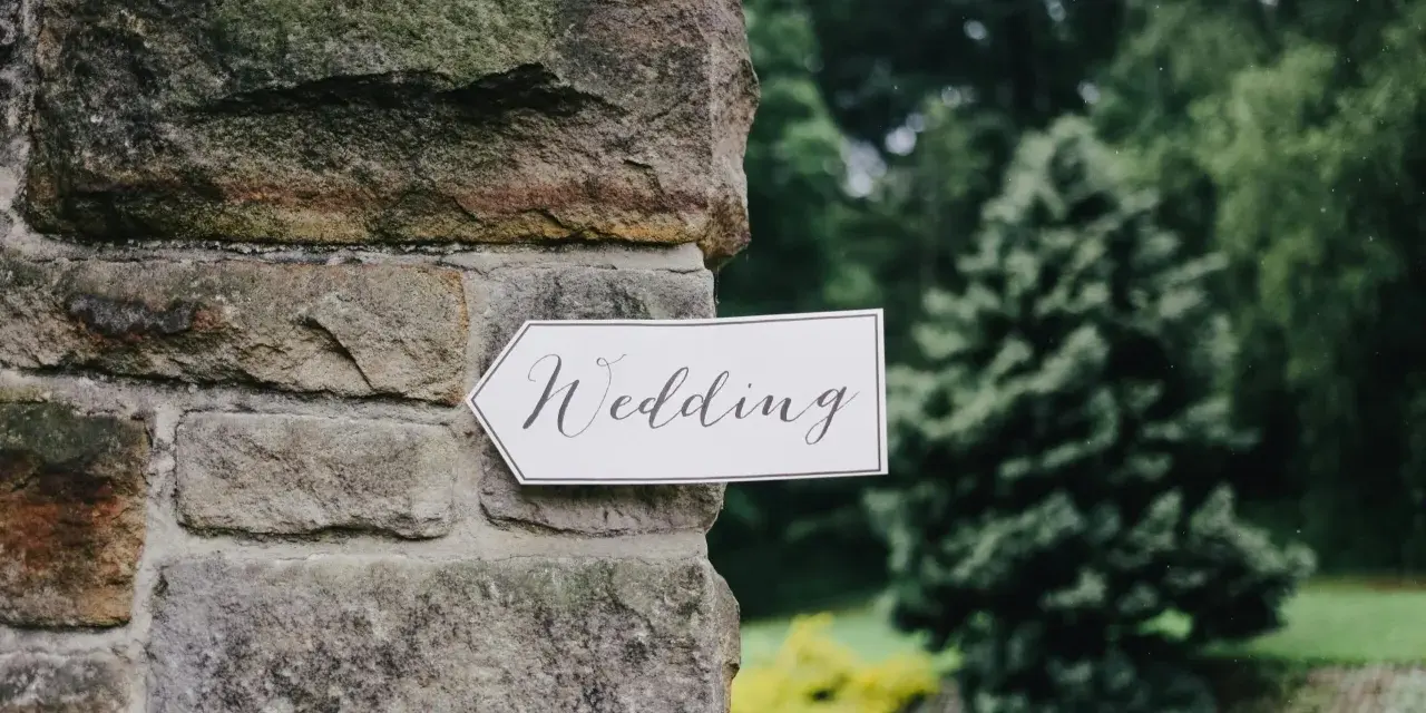 Strzałka z napisem "Wedding" wskazuje drogę do uroczystości, zapowiadając tradycyjny marsz weselny.