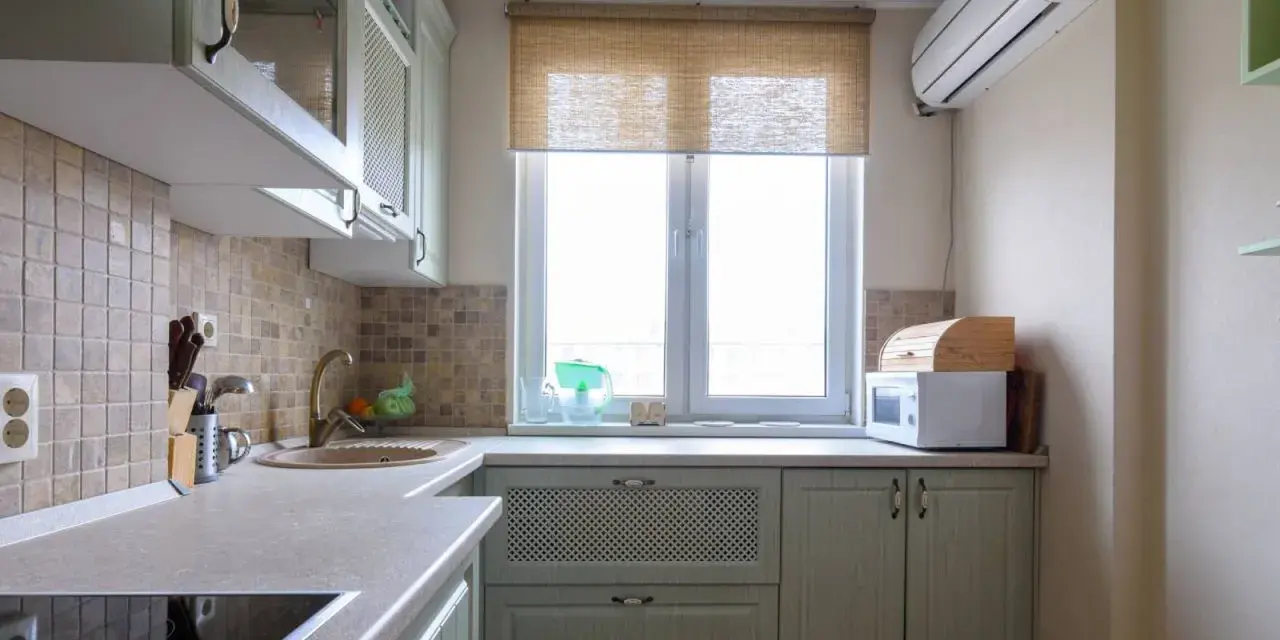 Cortinas de cocina de bambú sobre ventana, con microondas y panera de madera.