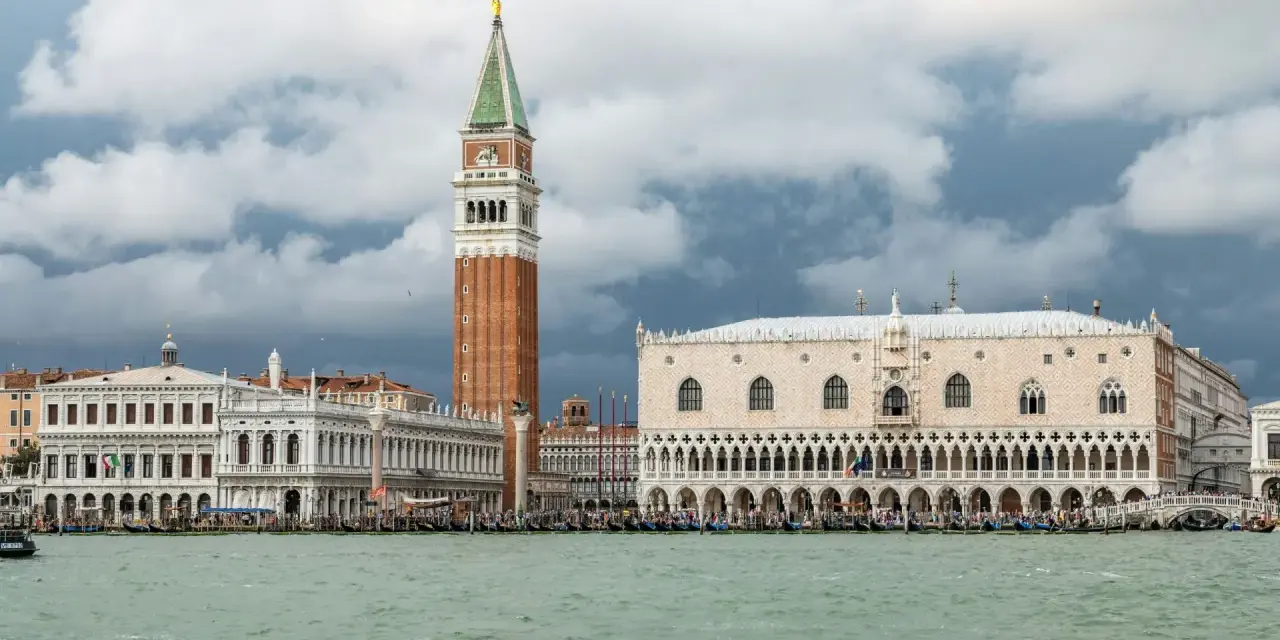 Weneckie budowle, w tym Pałac Dożów i Kampanila, na tle burzowych chmur. Venezia to miasto, które zachwyca.