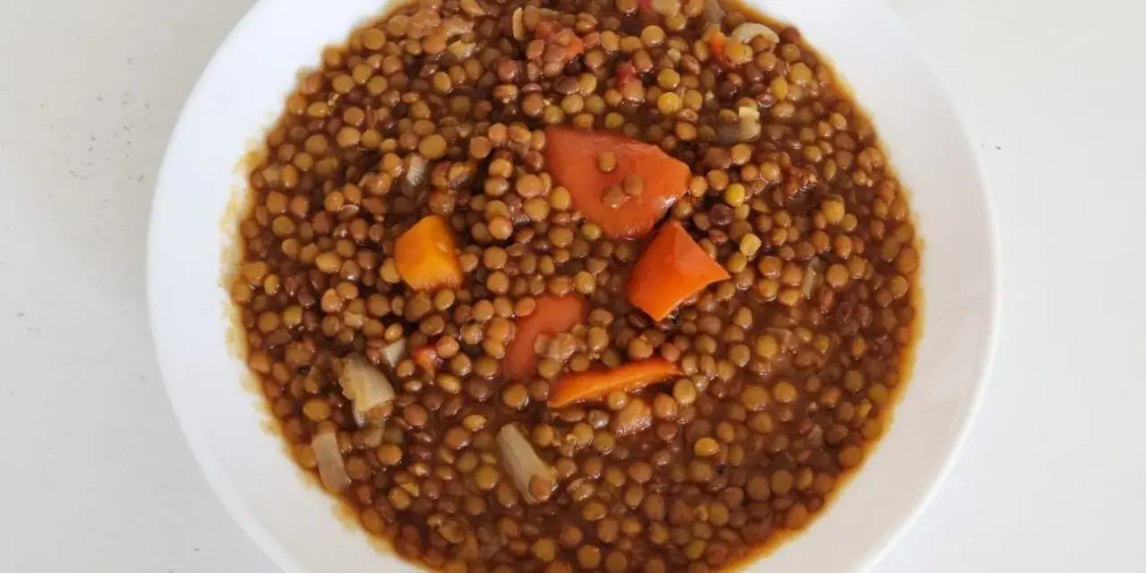 Un plato de lentejas guisadas con zanahoria y cebolla, cocinadas en olla express. Un plato reconfortante y rápido.