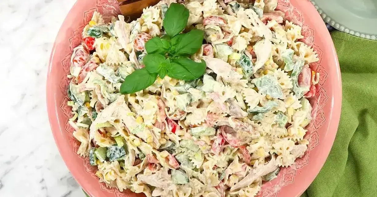 En krämig pastasallad med kyckling, grönsaker och en härlig basilika. Perfekt för ett snabbt pastasallad recept.