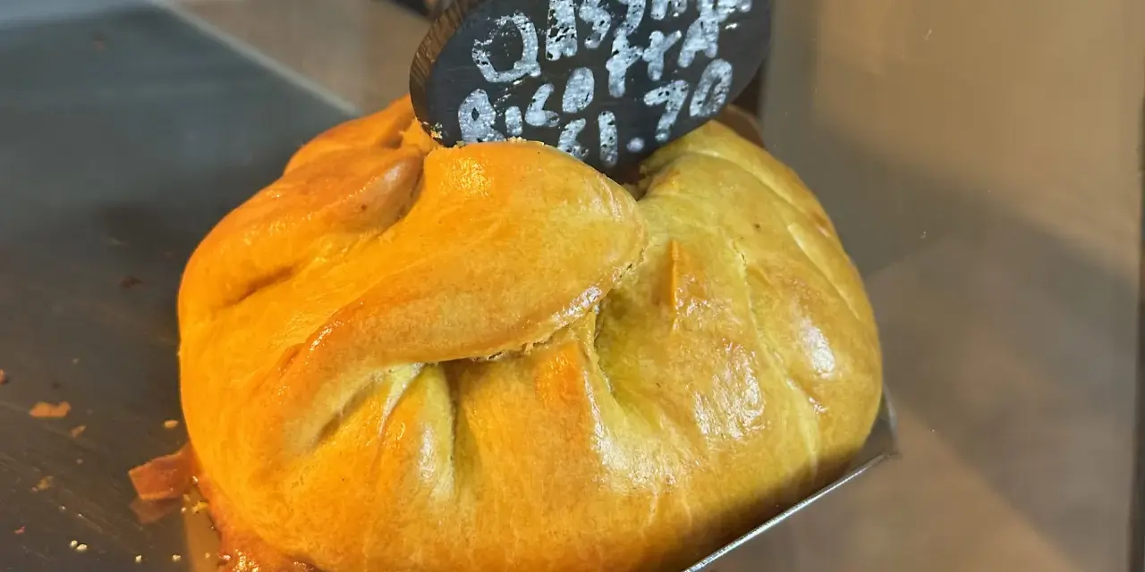 Złociste, pieczone ciasto z nadzieniem, typowe maltańskie jedzenie. Na tabliczce napis "Cassata Ricotta €1.70".