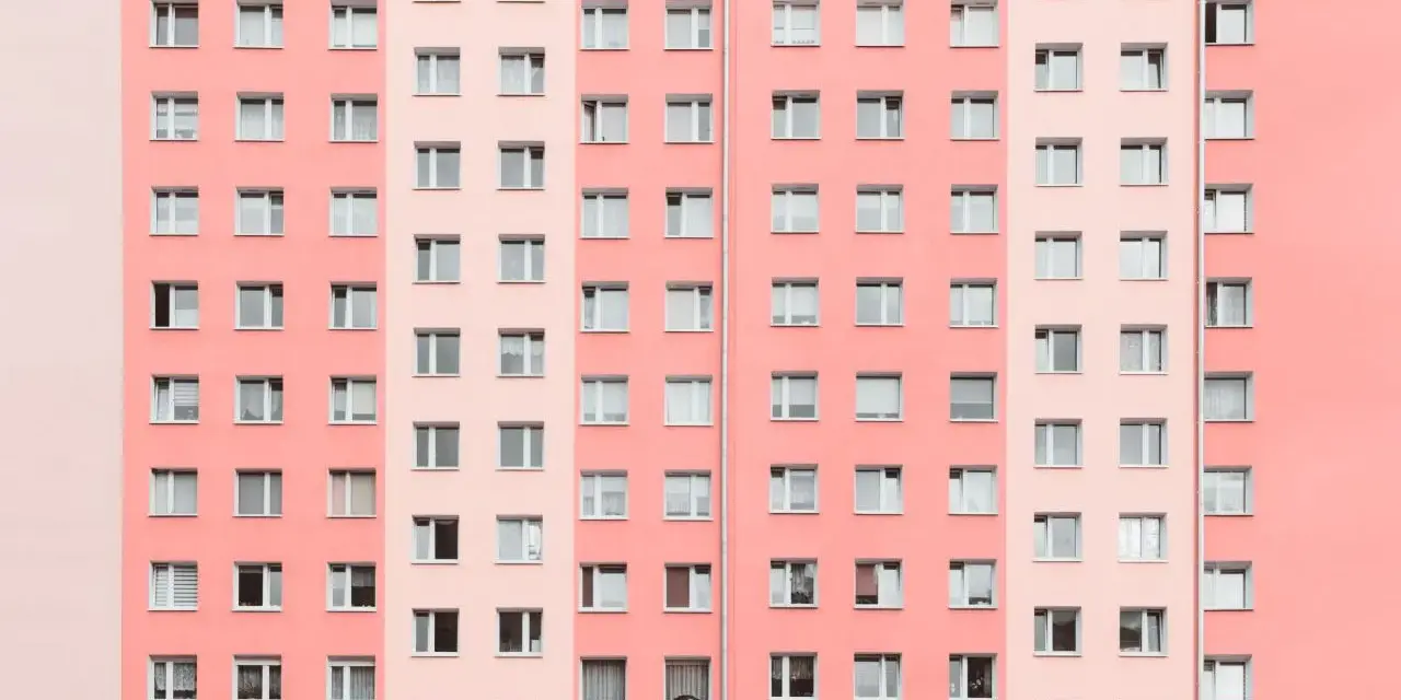 Pasteloza w architekturze: fasada bloku mieszkalnego w odcieniach różu i brzoskwini, z rzędami okien.